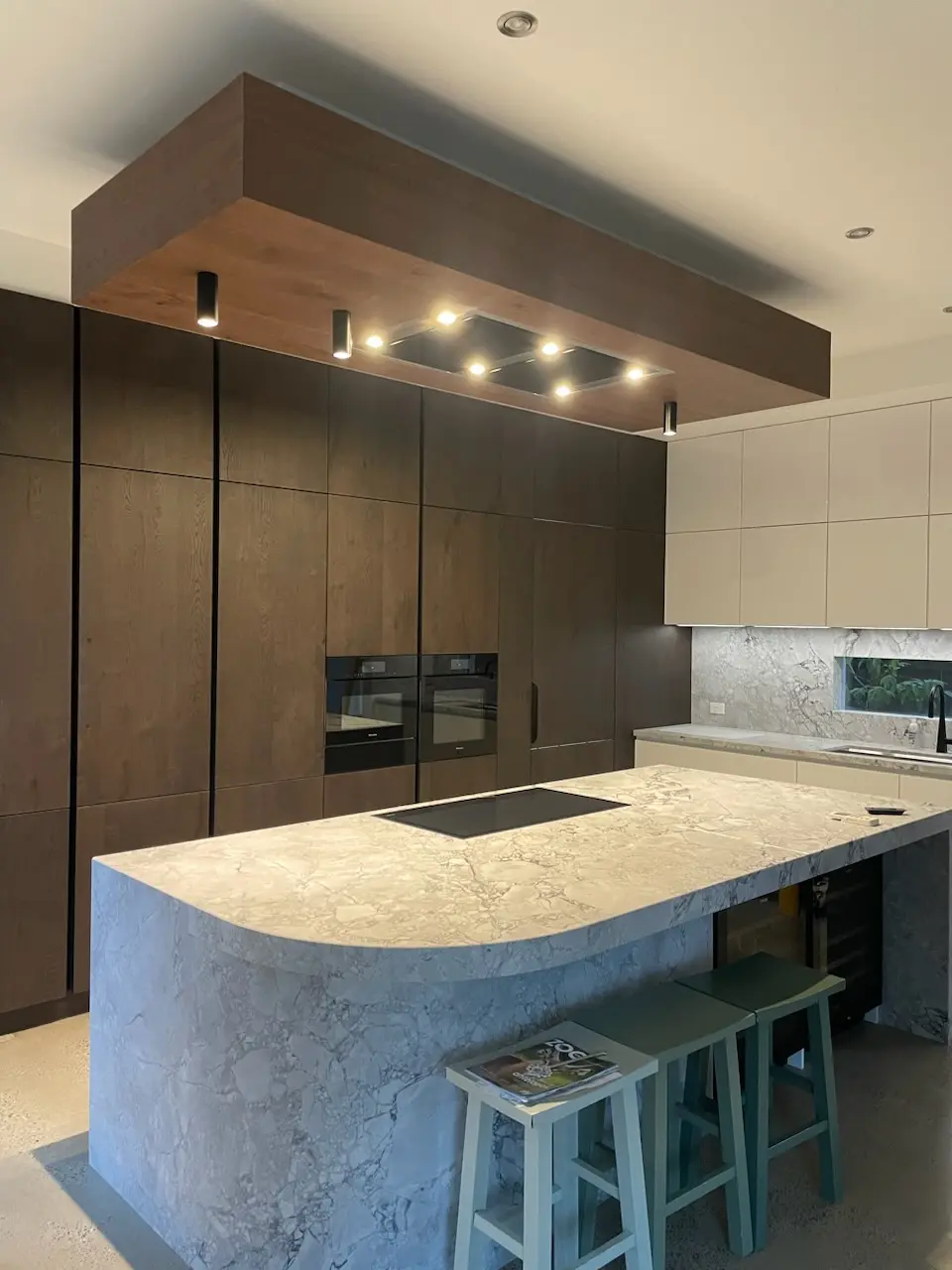 Luxury Häcker kitchen island with rounded grey stone benchtop and premium walnut timber cabinetry