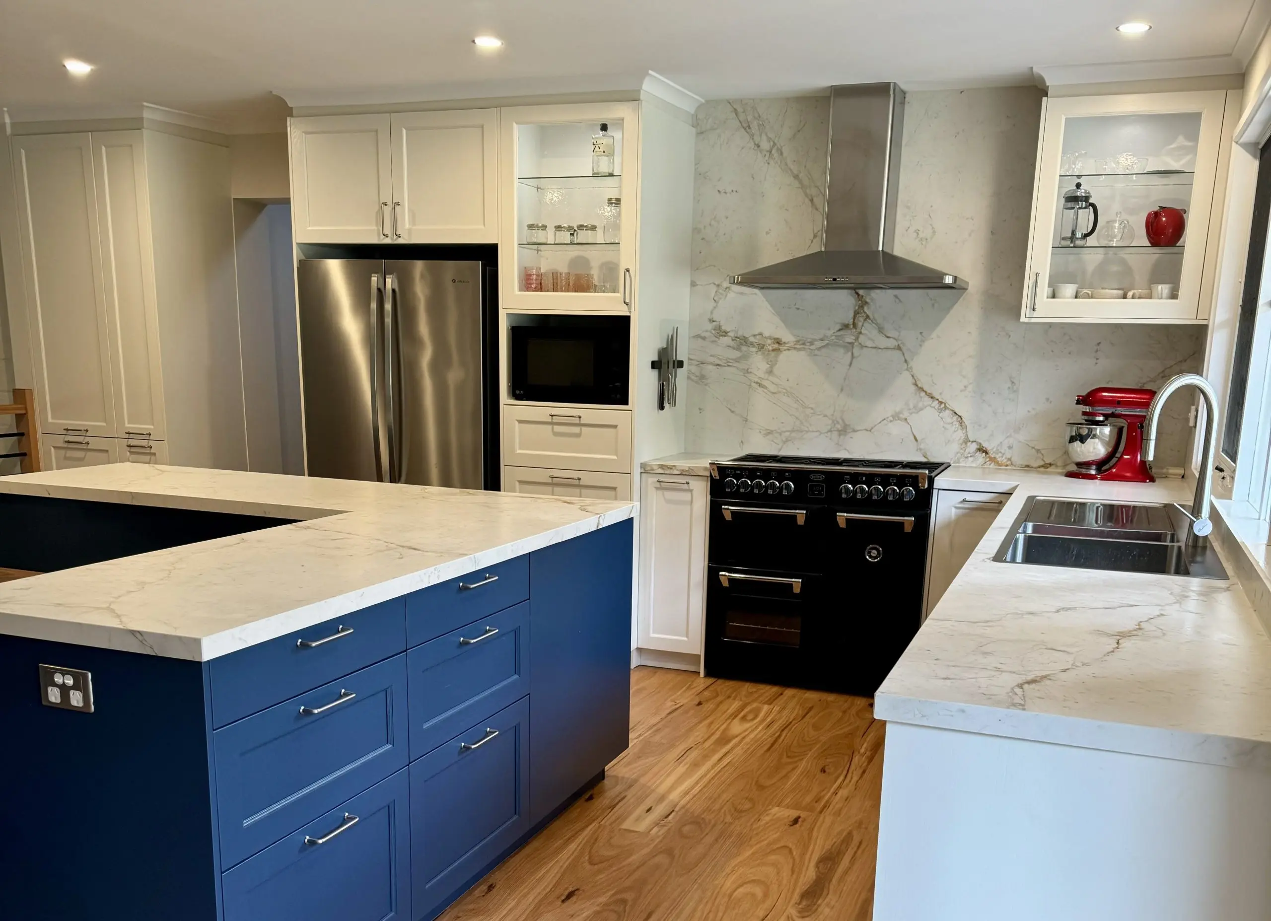 Bespoke Häcker luxury kitchen with marble stone benchtop and splashback, large l-shaped kitchen island, premium navy blue kitchen cabinetry.