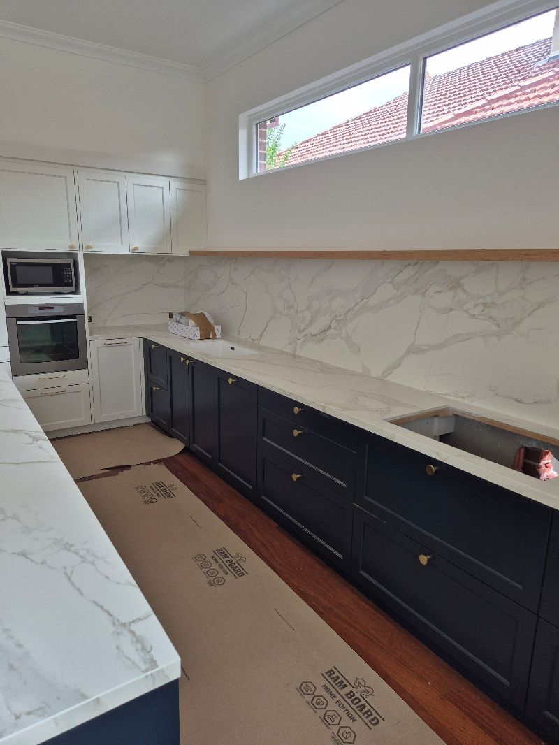 Luxury Häcker kitchen featuring navy blue shaker cabinetry and premium marble bench tops and splashback.
