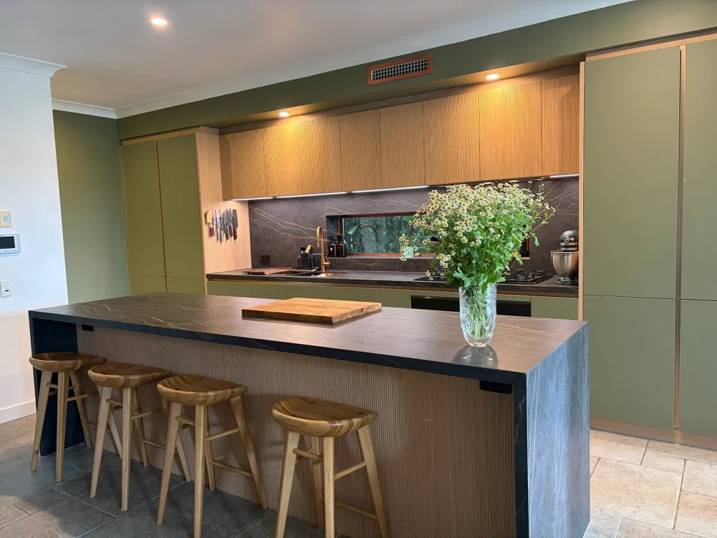 Premium German Häcker kitchen featuring olive green handleless cabinetry, premium oak timber fluted cabinets, and a waterfall marble kitchen island.